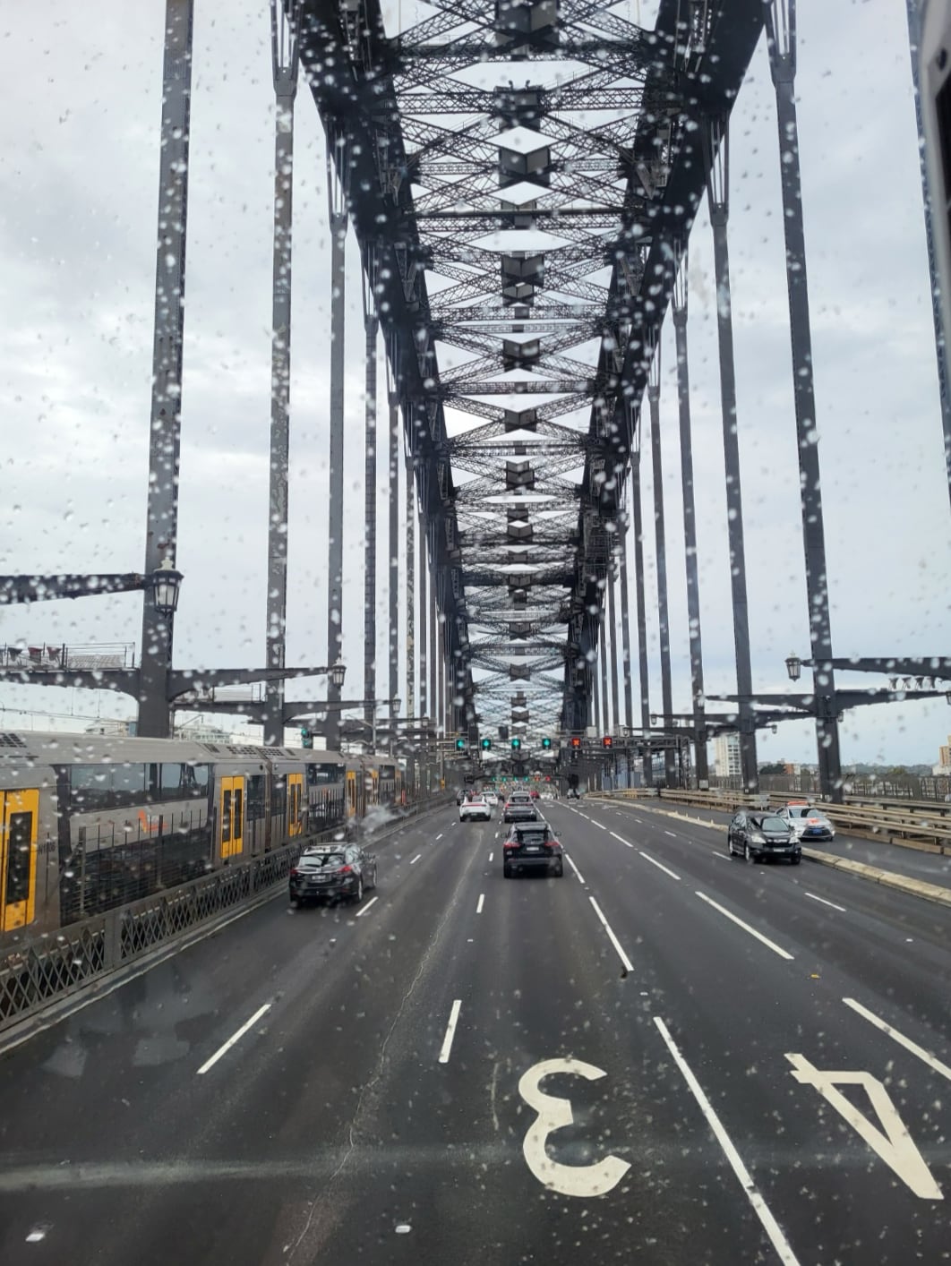Blick durch eine nasse Windschutzscheibe auf die Fahrbahn der Sydney Harbour Bridge