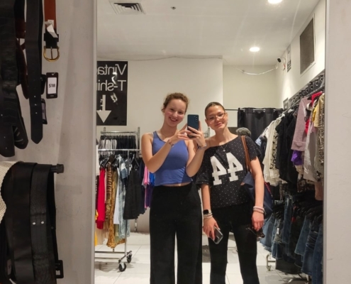 Carolina mit Freundin in einem Spiegel eines Bekleidungsgeschäftes